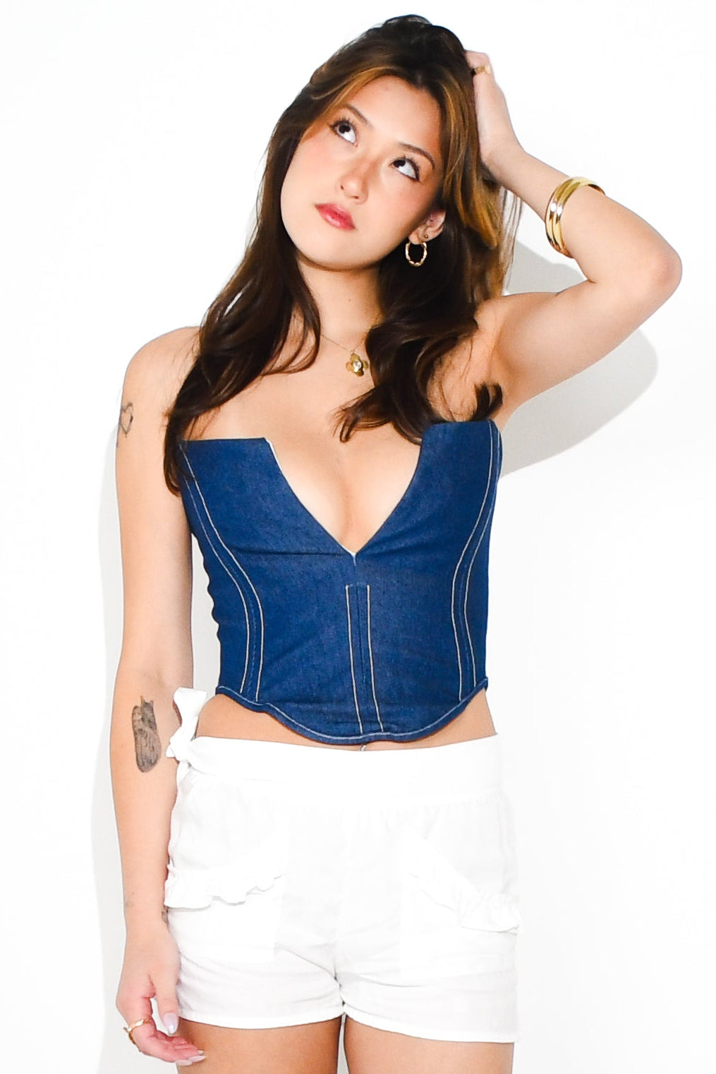 Woman wearing a blue corset, white shorts, and black boots on a white background